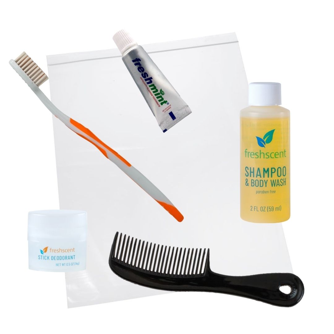 A 5 pc hygiene kit containing a toothbrush, toothpaste, shampoo, body wash, deodorant stick, and a comb, all displayed in an open clear plastic bag.